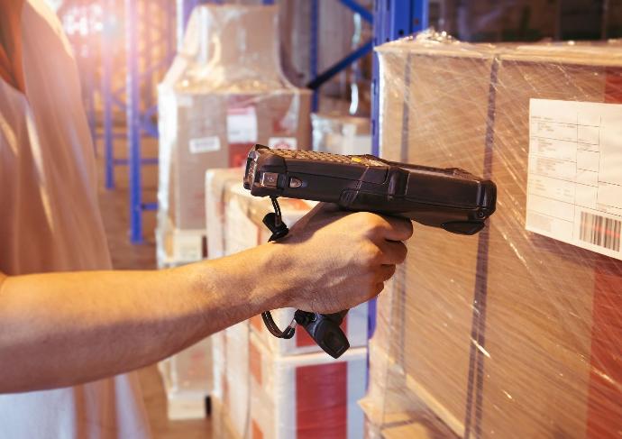 une personne utilise un terminal mobile dans un entrepôt de logistique